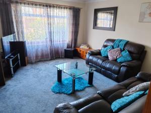 uma sala de estar com um sofá de couro e uma mesa de vidro em Wallace View - Holiday Home em Stirling