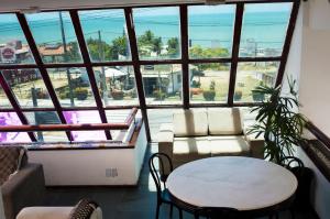 Habitación con mesa, sillas y ventana grande. en Happy Ponta Negra Express, en Natal