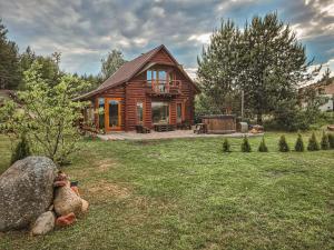 a log cabin in a yard with a large rock at Poilsis netoli Druskininkų in Druskininkai
