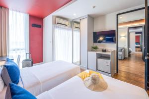a hotel room with two beds and a mirror at Blue Hippo Hotel in Ban Khlong Samrong