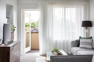sala de estar con sofá y ventana grande en Sunny Apartment in Quiet and Green Neighbourhood, en Sídney