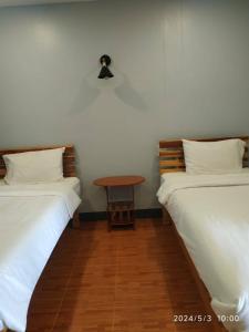 duas camas num quarto com uma mesa entre elas em เรือนวรา - Wara Guesthouse em Nan