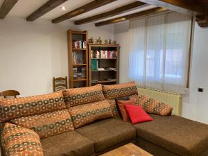 ein Wohnzimmer mit einem braunen Sofa und roten Kissen in der Unterkunft La casa del aguador, BTT y Senda Viva in Alfaro