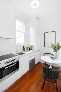 a white kitchen with a table and a sink at Cosy nook in inner-city Victorian mansion in Sydney