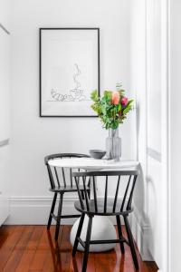 a table with a vase of flowers and two chairs at Cosy nook in inner-city Victorian mansion in Sydney