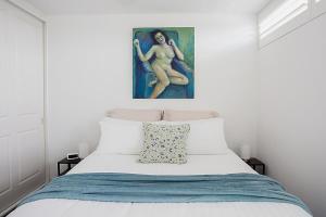 a bedroom with a bed with a painting on the wall at Treetop Retreat Five Minute Stroll To The Beach in Sydney