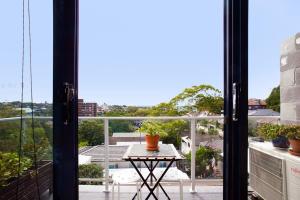 a balcony with a table and a view of the city at Treetop Retreat Five Minute Stroll To The Beach in Sydney