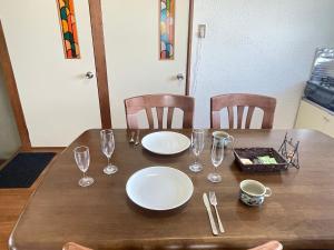 a wooden table with plates and wine glasses on it at Azumi Relax Lodge 2 in Azumino