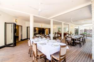 uma sala de jantar com mesas e cadeiras brancas em Nkosi Guest Lodge em Victoria Falls