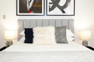 a bedroom with a white bed with three pictures on the wall at Charming Studio With Balcony in Inner-City Glebe in Sydney