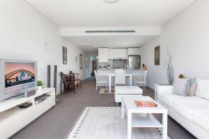 een woonkamer met witte meubels en een keuken bij Spacious Modern Apartment In Sydney's North Shore in Sydney