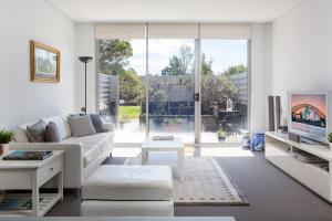 een woonkamer met een witte bank en een groot raam bij Spacious Modern Apartment In Sydney's North Shore in Sydney