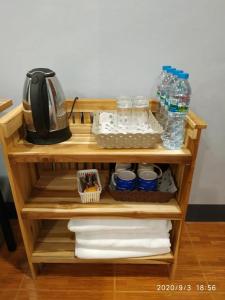 uma prateleira de madeira com garrafas de água, copos e toalhas em เรือนวรา - Wara Guesthouse em Nan