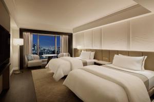 um quarto de hotel com três camas e vista para a cidade em The Westin Tokyo em Tóquio