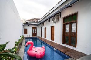 two pink inflatable flamingos in a swimming pool next to a house at Ndalem Pringgo in Timuran