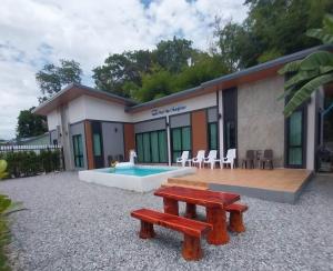 a house with a pool and benches in front of it at Vamin Poolvilla Chiangkhan Loei วามินทร์พูลวิลล่า เชียงคาน เลย - วามินทร์ รีสอร์ท in Chiang Khan