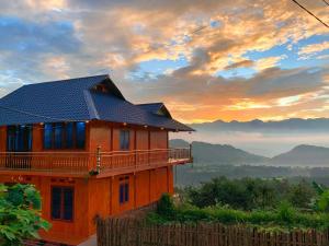 a house on a hill with a sunset in the background at Homestay Trúc Sơn in Hong Ha