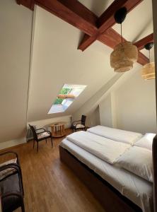 K8-5 Apartments في نيدا: غرفة نوم بسرير وكراسي في العلية