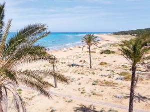 a sandy beach with palm trees and the ocean at Mandola Rosa Grecotel Boutique Resort in Loutra Killinis