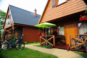 dom z rowerami zaparkowanymi przed nim z parasolką w obiekcie CAŁOROCZNE DOMKI NAD MORZEM I JEZIOREM w mieście Jezierzany