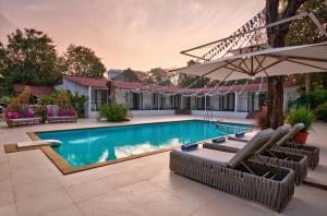 a swimming pool with chairs and an umbrella at Blu Resorts in Vagator