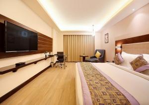a hotel room with a large bed and a flat screen tv at Balwood Suites Near Delhi Airport in New Delhi