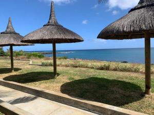 a group of straw umbrellas on the beach at Modern Oceanview Apartment D1 in Flic-en-Flac