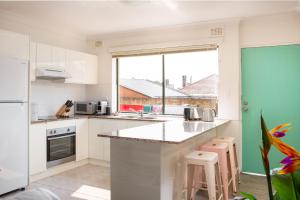 Cosy 2-Bed Apartment in the Heart of Strathfield في سيدني: مطبخ مع دواليب بيضاء ونافذة كبيرة