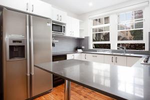 een keuken met witte kasten en een roestvrijstalen koelkast bij Sunlit 2-bed Apartment Metres From the Beach in Sydney