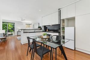 een keuken en eetkamer met een glazen tafel en stoelen bij Classy Beachside Unit with Parking and Gym in Melbourne