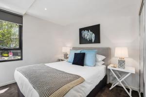 een slaapkamer met een groot bed met blauwe kussens bij Chic 2-Bed Oasis in South Melbourne's Heart in Melbourne