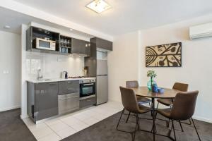een keuken en eetkamer met een tafel en stoelen bij Chic 2-Bed Oasis in South Melbourne's Heart in Melbourne