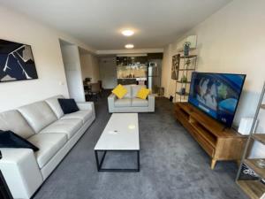 een woonkamer met een bank en een flatscreen-tv bij Chic 2-Bed Oasis in South Melbourne's Heart in Melbourne
