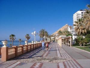 een man en vrouw die over een stoep lopen bij het strand bij Benalmadenapartments BBQ Evita Beach Club in Benalmádena