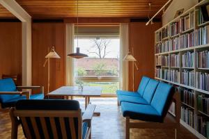 a library with blue chairs and a table and bookshelves at Løgumkloster Refugium in Løgumkloster