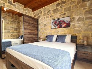 New Villa Kalimera, view to Falasarna beach في Plátanos: غرفة نوم بسرير وجدار حجري