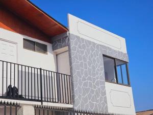 a home with a stone wall and a balcony at Departamento Familiar Privado in Antofagasta