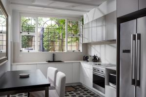 a kitchen with white cabinets and a table and some windows at Elegant 3-Bed Heritage House with Swimming Pool in Sydney