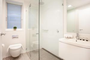 a white bathroom with a toilet and a sink at Spacious 3-Bed Family House with Courtyard in Sydney