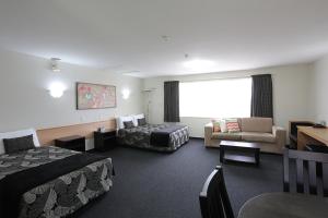 een hotelkamer met 2 bedden en een bank bij Homestead Villa Motel in Invercargill