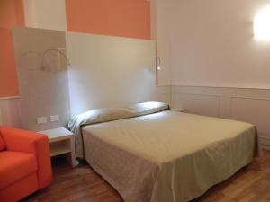 a bedroom with a bed and an orange chair at Affittacamere Via Mazzini in Stresa