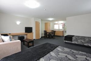 a hotel room with a bed and a table and chairs at Homestead Villa Motel in Invercargill