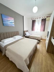 a bedroom with two beds and a tv on the wall at Odi Apartments in Durrës