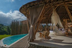 a resort with a swimming pool and a bed and chairs at Nivriti Bali in Sidemen