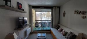 sala de estar con sofá y balcón en L ANTARES residence les etoiles la foux d allos joli studio 4 couchages en La Foux