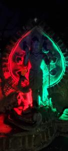 a statue of a man on a stage with red and green lights at Jungle river humbhaha hostel in Kataragama
