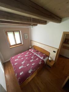 ein Schlafzimmer mit einem Bett mit einer lila Bettdecke und einem Fenster in der Unterkunft Agriturismo Maso Fumas in Canale dʼAgordo