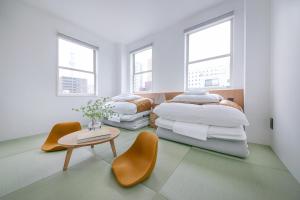 two beds in a room with two chairs and a table at ぷふか浅草 in Tokyo
