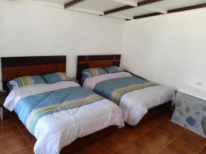 2 Betten in einem Zimmer mit weißen Wänden in der Unterkunft casa montañista lodge & camping in Huaraz