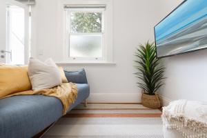 a living room with a blue couch and a plant at Chic Studio With Patio 20 min From CBD in Sydney